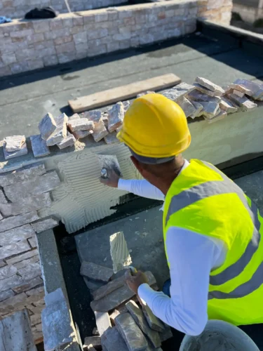 Porti commerciali di Manfredonia: operaio posa il rivestimento in pietra di un muretto